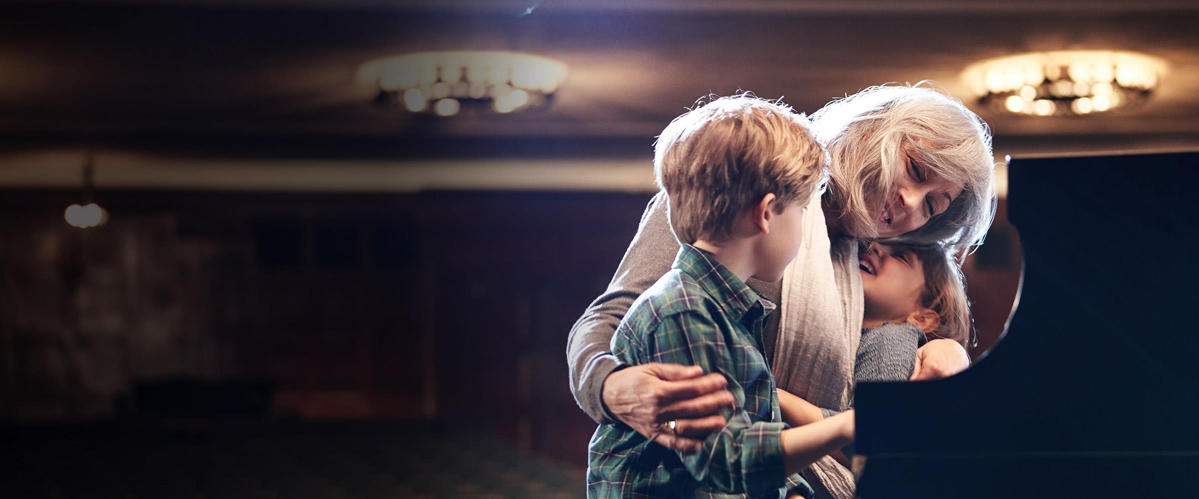 Woman playing piano with grandkids wearing LiNX Quattro hearing aids