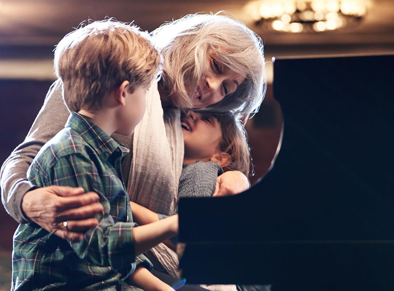 Woman playing piano with grandkids wearing LiNX Quattro hearing aids