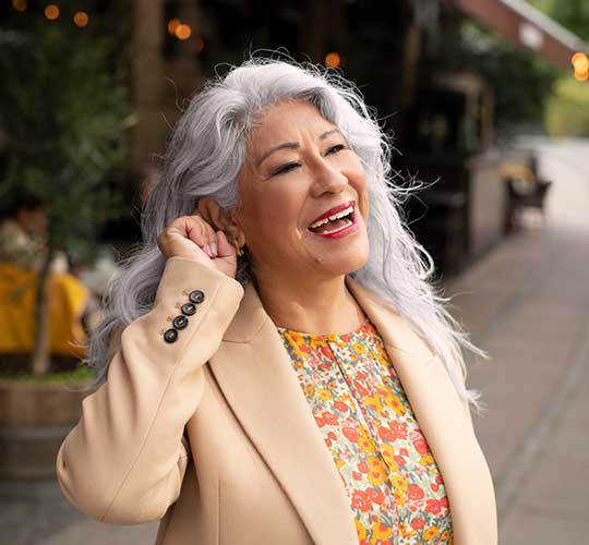Smiling woman pushing button on her hearing aid